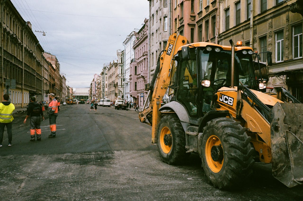 portfolio-01 City street construction scene with workers and JCB excavator.